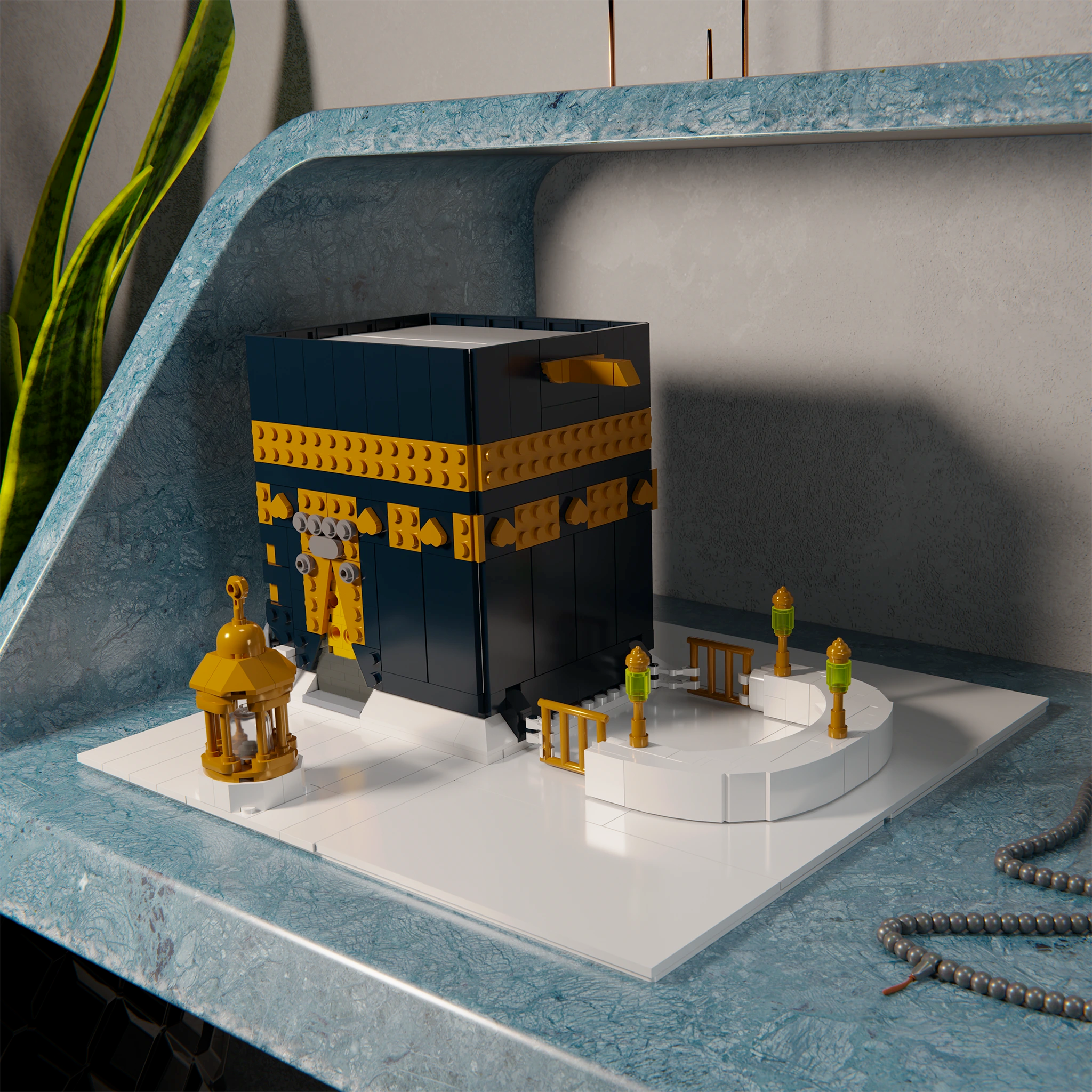 Islamic LEGO-compatible Kaaba model from ALIF Bricks on a blue desk with prayer beads and green plant in the background